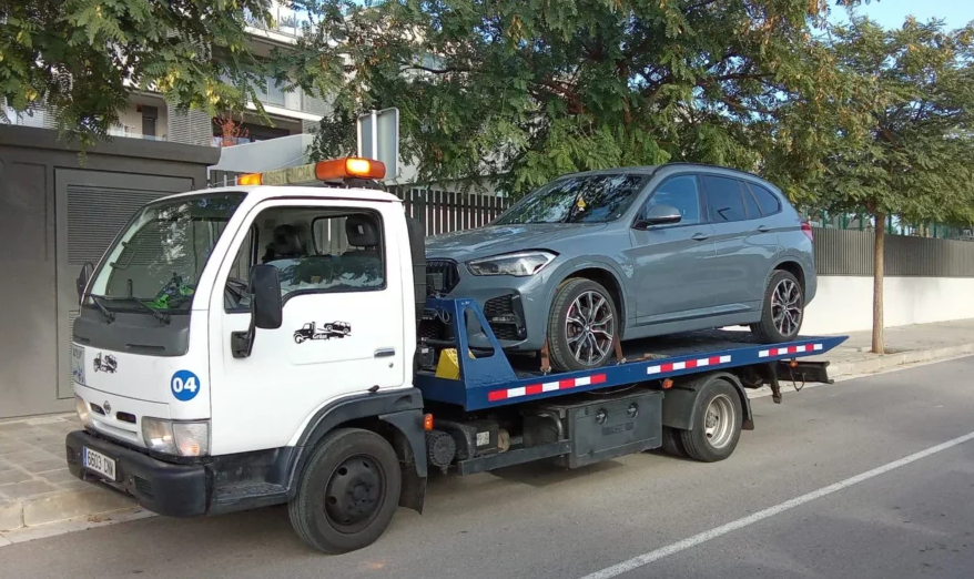 Coche cargado sobre grúa de plataforma — servicio de recogida a domicilio